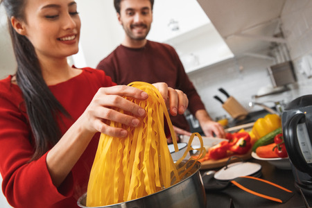 Young couple having romantic evening at home in the kitchen cooking meal together close-upの写真素材