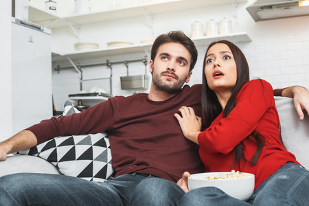 Young couple having romantic evening at home together watching mysteryの写真素材