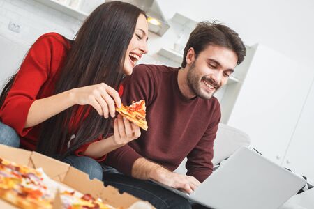Young couple having romantic evening at home watching comedy on laptopの写真素材