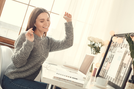 Young woman freelancer indoors home office concept winter atmosphere sitting listening musicの写真素材