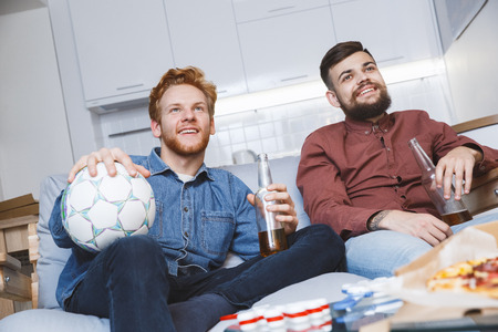 Men watching sport on tv together at home great timeの写真素材