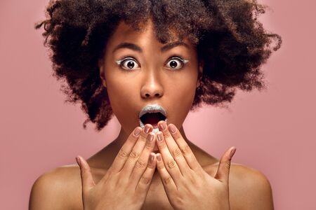 Young african woman isolated on pink wall studio fashion stylish makeup shockedの写真素材