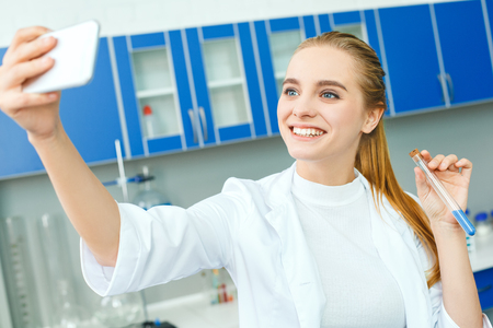 Young chemistry teacher in school laboratory work standing selfie photosの写真素材