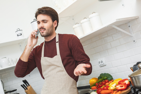 Young man cooking romantic dinner at home phone callの写真素材