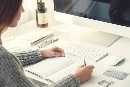 Young woman freelancer indoors home office concept casual style sitting writingの写真素材