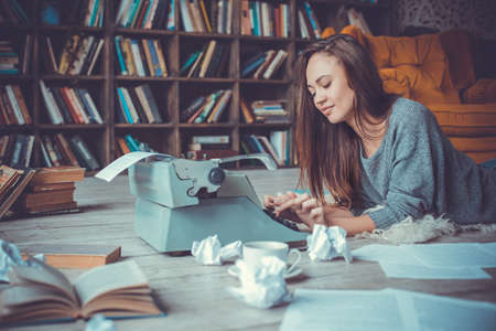 Young woman writer in library at home creative occupationの写真素材