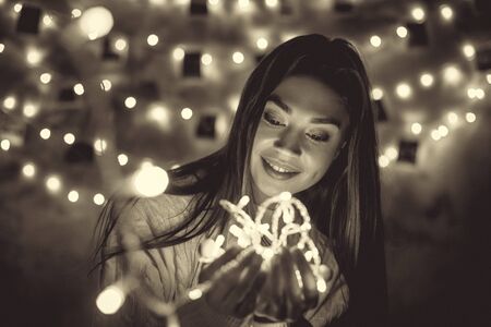 Young woman weekend at home decorated bedroom holding lightsの写真素材