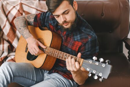 Young guitarist hipster at home sitting playing guitar top viewの写真素材