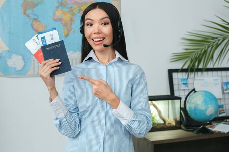 Young female travel agent consultant in tour agency showing documentsの写真素材