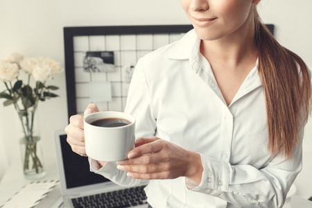 Young woman freelancer indoors home office concept formal style holding coffee cupの写真素材