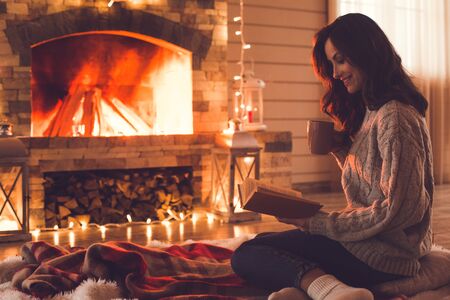 Young woman near fireplace at home winter conceptの写真素材