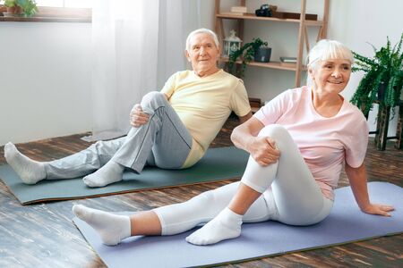Senior couple doing yoga together at home health care leg stretchingの写真素材