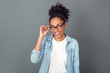 Young african woman isolated on grey wall studio casual daily lifestyle student laughingの写真素材