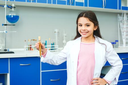 Little child with learning class in school laboratory standing holding vialの写真素材
