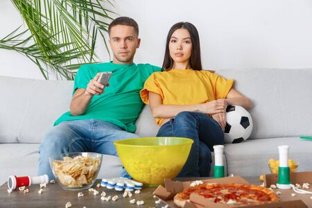 Young couple sport fans watching match switching channelの写真素材