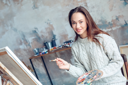 Young woman artist painting at home creative drawing smilingの写真素材