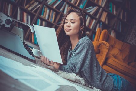 Young woman writer in library at home creative occupation reading pageの写真素材