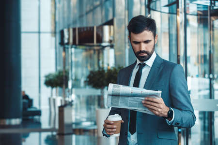 Businessman in a fromal suit in a business center morning newspaper and coffeeの写真素材