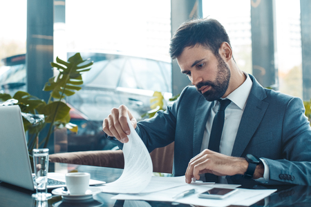 Businessman sitting in a business center restaurant looking through contractの写真素材