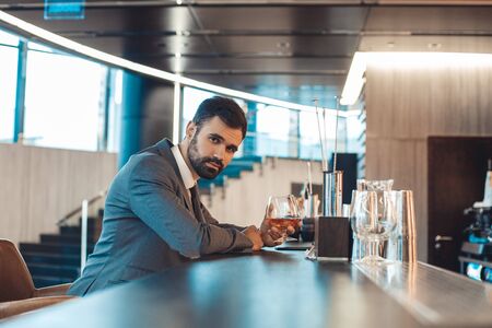 Businessman sitting at a business center bar counter drinking alcohol