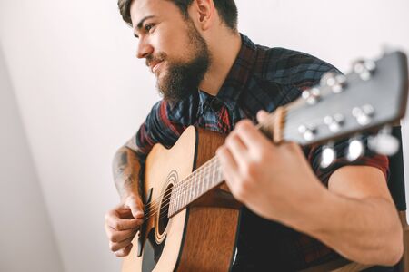 Young guitarist hipster at home playing guitar using mediator close-upの写真素材