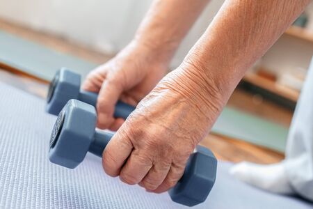 Senior man exercise at home health care holding dumbbells down close-upの写真素材