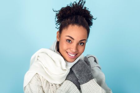 Young african woman isolated on blue wall studio winter concept tendernessの写真素材
