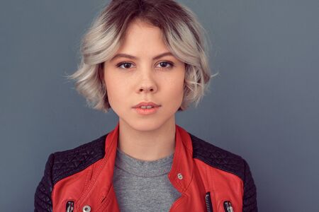 Young woman standing in leather jacket isolated on grey wall sensuality close-upの写真素材