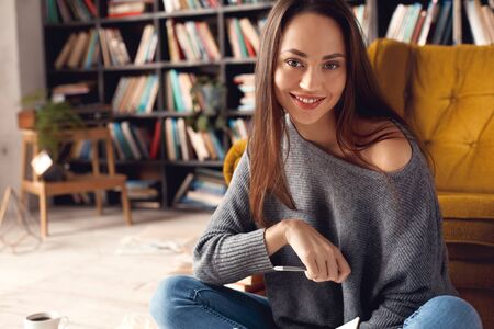 Young woman student in library at home smiling cheerfulの写真素材
