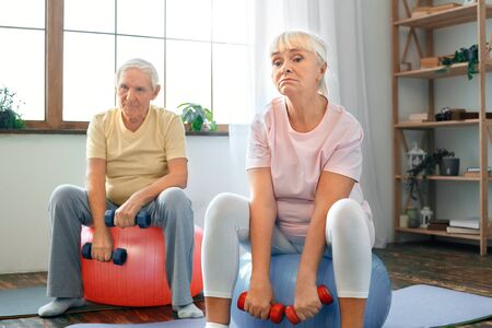 Senior couple exercise together at home doing aerobics with dubbells downの写真素材