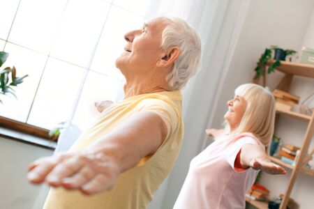 Senior couple exercise together at home health care gymnastic hands asideの写真素材