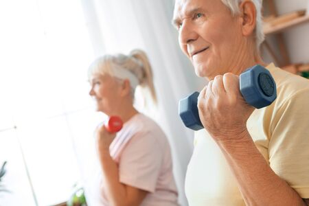 Senior couple exercise together at home health care with dumbbells close-upの写真素材