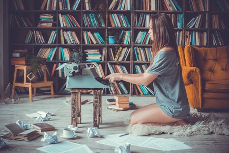 Young woman writer in library at home creative occupation typing concentratedの写真素材