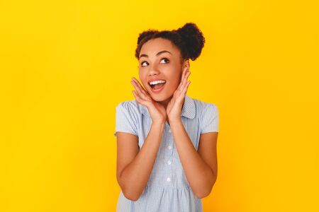 Young african woman isolated on yellow wall studio cute girl style surprisedの写真素材