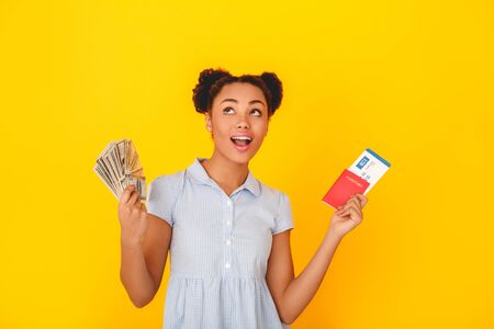 Young african woman isolated on yellow wall studio cute style traveler concept dreamingの写真素材