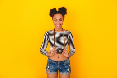 Young african woman isolated on yellow wall studio teen style photographerの写真素材