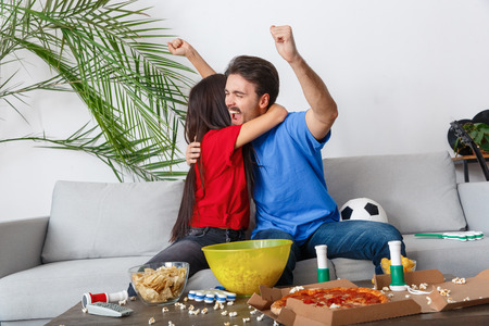 Young couple sport fans watching match hugging cheerfulの写真素材