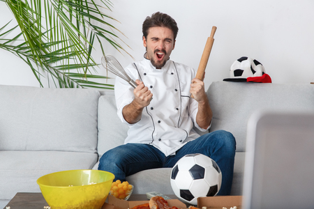 Young man chef sport fan watching match goalの写真素材