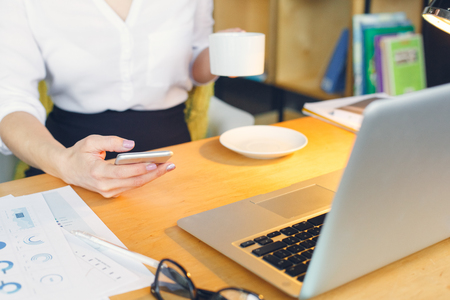 Pregnant business woman working at office motherhood sitting holding smartphoneの写真素材