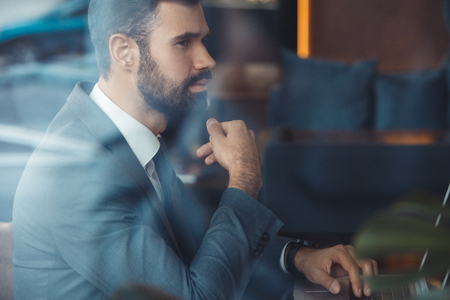 Businessman sitting in a business center restaurant with laptop thoughtfulの写真素材