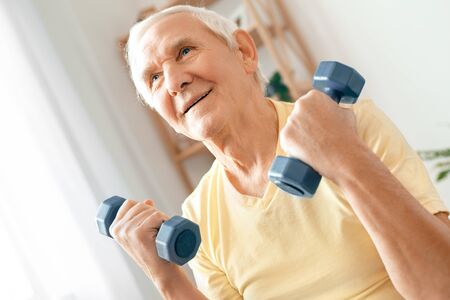 Senior man exercise at home health care sitting holding dumbbellsの写真素材