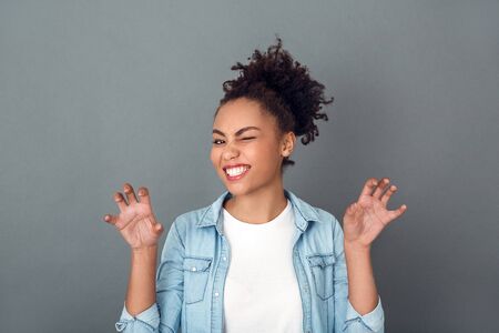 Young african woman isolated on grey wall studio casual daily lifestyle cat poseの写真素材