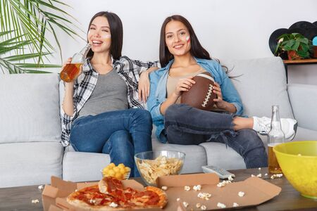 Female friends sport fans watching match holding rugby ballの写真素材