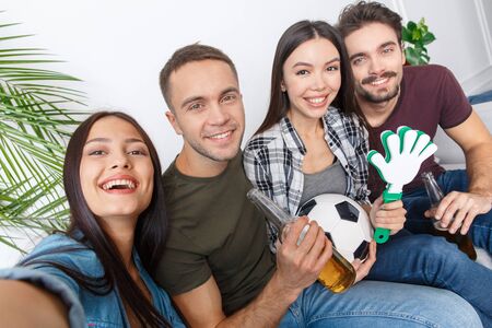 Group of friends sport fans watching soccer match taking selfie photosの写真素材