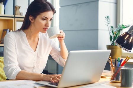 Pregnant business woman working at office motherhood sitting using laptop drinking teaの写真素材