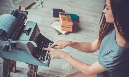 Young woman writer in library at home creative occupation typing article close-upの写真素材