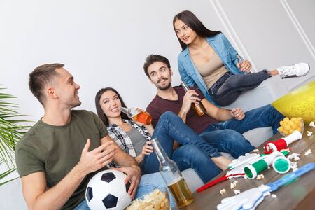 Group of friends sport fans watching soccer match talkingの写真素材