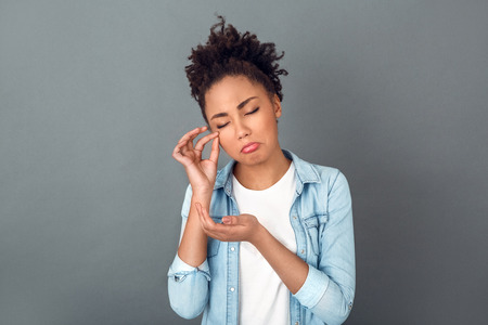 Young african woman isolated on grey wall studio casual daily lifestyle crying grimaceの写真素材