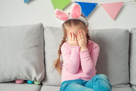 Little cute girl at home easter celebration concept in bunny ears crying upsetの写真素材