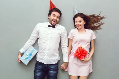 Young couple top view isolated on grey background holding gift boxesの写真素材